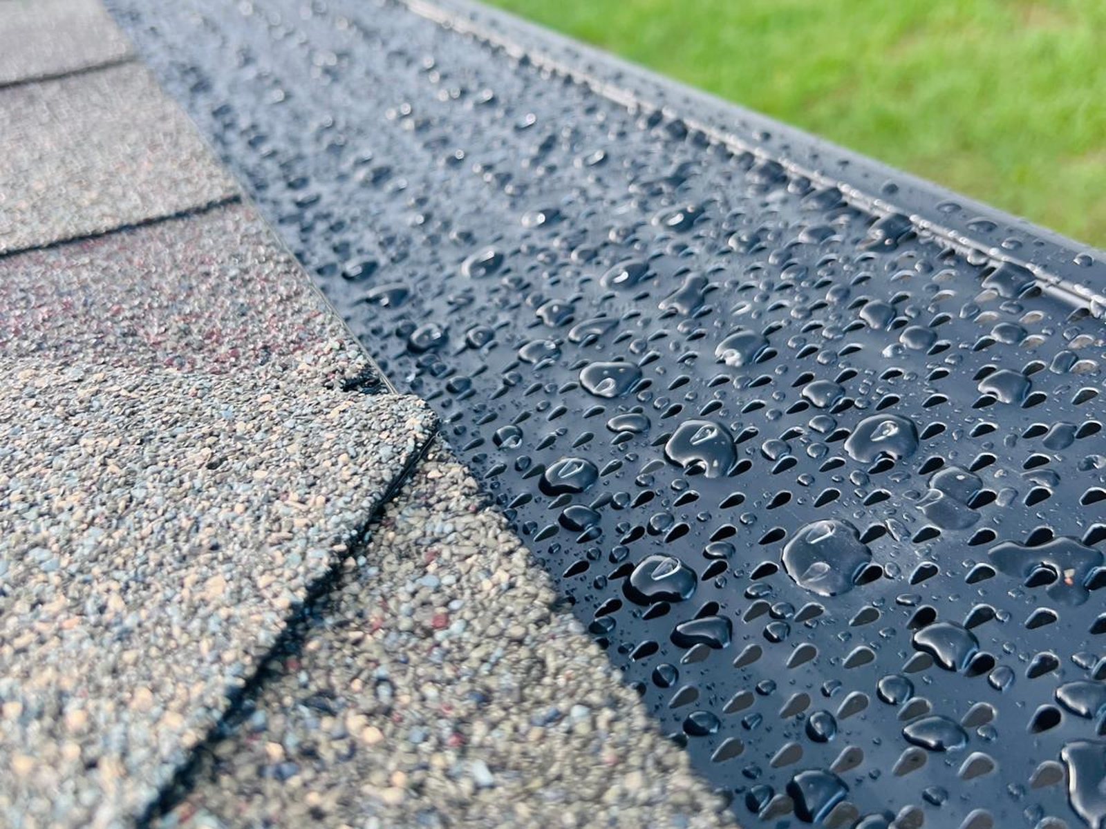 Black perforated aluminum gutter guard installed along the shingle line of a Central Florida home after rain