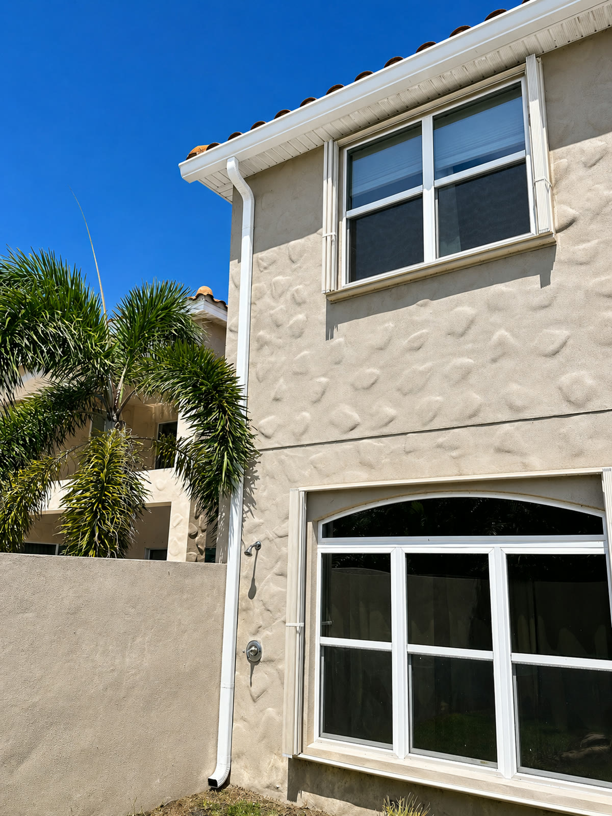 Two-story Central Florida home with a clay tile roof and a white seamless gutter installed by Gutters C2U.