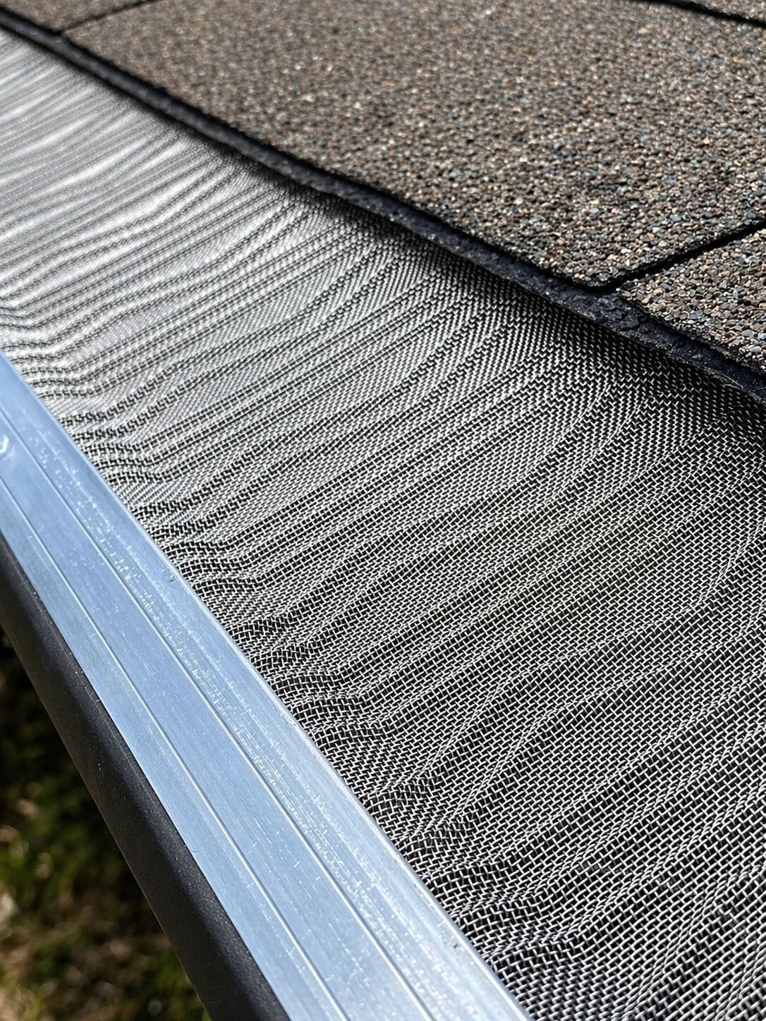 Close-up of a mesh gutter guard on a shingle roof