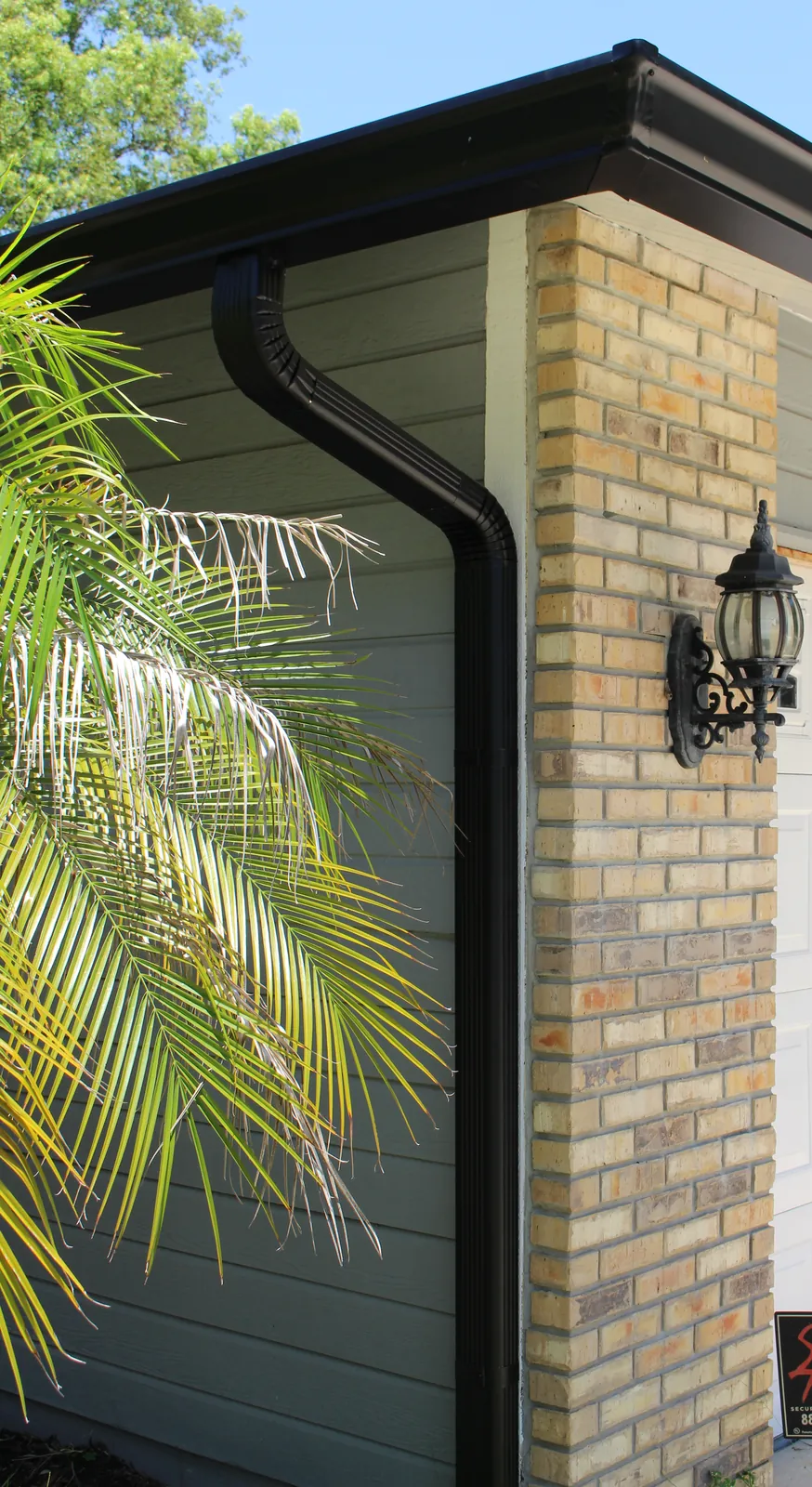 Dark bronze downspout beside a brick garage column in Longwood, FL