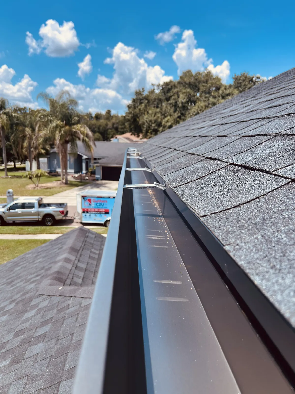 New seamless gutter along the roofline in Oviedo, FL, with the Gutters C2U trailer parked out front