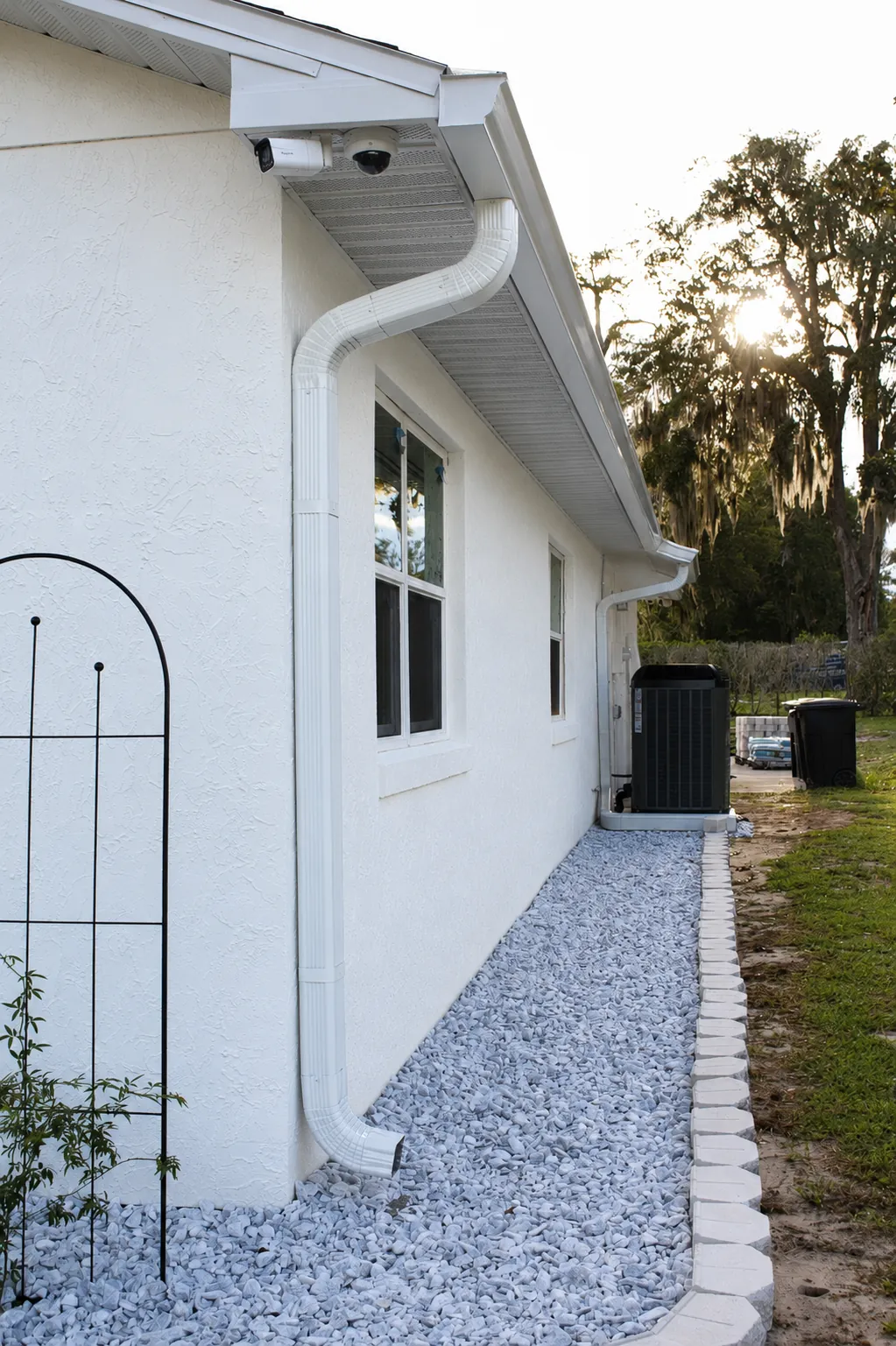 White downspout draining onto a gravel strip in Oviedo, FL