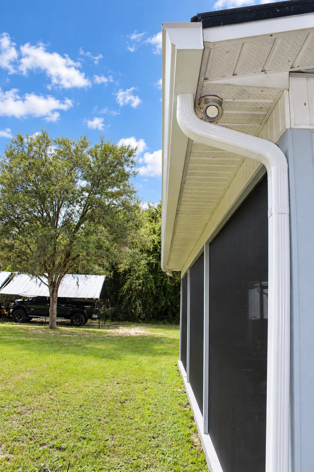 White seamless gutters and downspout along a screened porch in Oviedo, FL